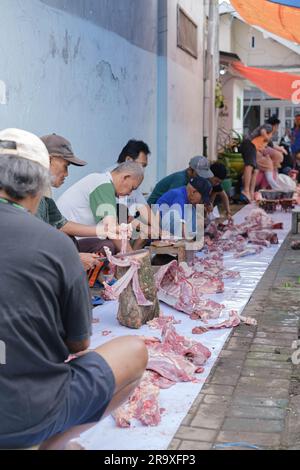 MALANG, INDONESIA - 29 giugno 2023: Ritratto o verticale di molte persone che tagliano carne di capra e manzo durante Eid al-Adha o Idul Adha Foto Stock