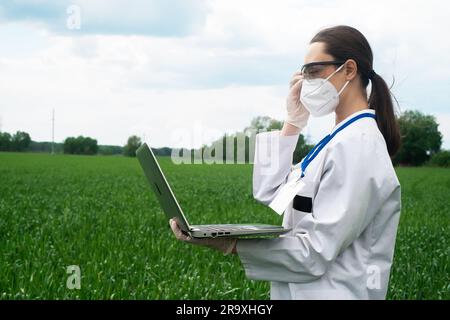 Agronomo che utilizza tablet e tecnologia nel campo del mais agricolo. L'agricoltore cammina nel campo con un tablet. Donna biologa con notebook Foto Stock