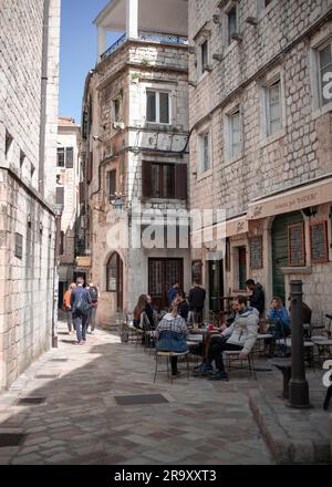 Kotor, Montenegro, 12 aprile 2023: Un caffè all'aperto situato in una tipica stradina acciottolata della città vecchia Foto Stock