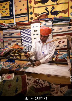 Udaipur, India - 29 dicembre 2022 : uomo Rajasthani vecchio e non identificato, in abbigliamento tradizionale, che crea tappeti a mano Foto Stock