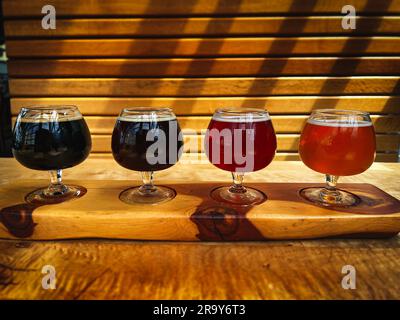 Un primo piano di quattro birre colorate su una pagaia di legno in una giornata di sole Foto Stock