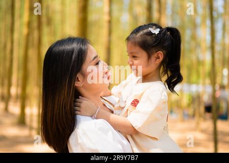 Madre che tiene la figlia carina e ridendo insieme nel parco della pineta Foto Stock
