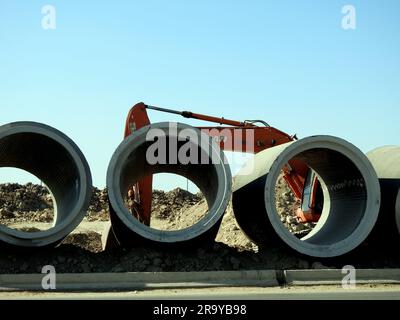 Cairo, Egitto, 24 giugno 2023: Un escavatore di scavo per la preparazione di grandi parti di tubi dell'acqua in loco, tubi di sanificazione, miglioramento dell'infrastruttura a Foto Stock