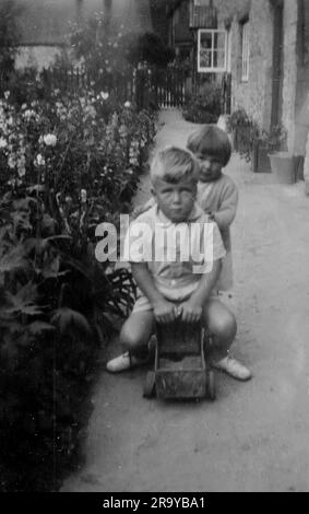 Una ragazza che spinge un ragazzo su un carrello. Surrey, c1930. Si tratta di una fotografia tratta da un album di scatti, durante l'occupazione della Palestina da parte dell'esercito britannico, con foto provenienti dalla Palestina e dal Regno Unito, tra cui devil's Jump vicino a Churt nel Surrey e devil's Punch Bowl. L'addestramento sembra essere a Hursley Camp, vicino a Winchester. La Gran Bretagna amministrò la Palestina per conto della società delle Nazioni tra il 1920 e il 1948, un periodo denominato "mandato britannico”. Foto Stock