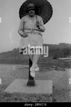 Una signora, con un ombrellone, seduta su una struttura simile a un dissuasore, vicino a Gibbet Hill a Hindhead, Surrey. Foto da un album di famiglia di immagini scattate principalmente nel Regno Unito, intorno al 1929. La famiglia viveva a Witley, nel Surrey, e aveva alcuni legami con l'esercito. Foto Stock