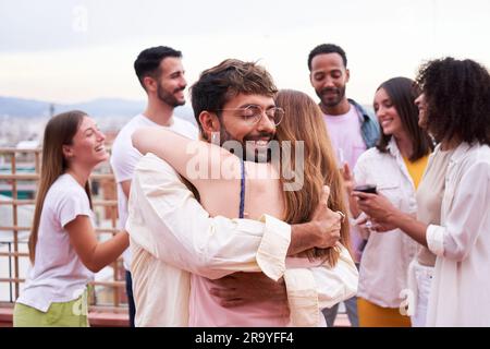 Due amici che si abbracciano all'aperto durante una riunione sociale. Foto Stock