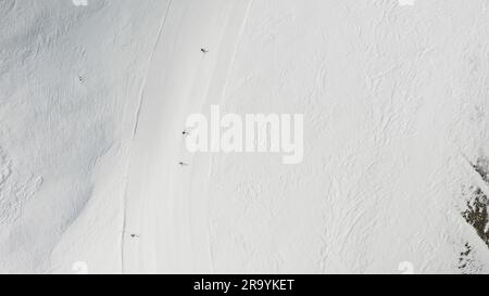 Persone che praticano lo snowboard e lo sci presso la stazione sciistica. Sciatori, snowboarder che percorrono piste innevate di montagna. Sport invernali all'aperto. Antenna, vista dall'alto Foto Stock