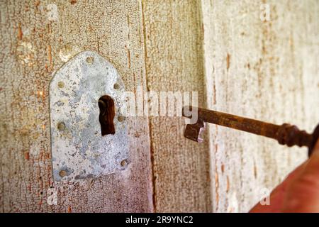 Pomello in ottone con chiave inserita nel suo vecchio foro per serratura, che consente l'accesso a una porta Foto Stock