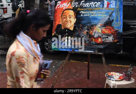 Mumbai, India. 29 giugno 2023. Una donna che tiene in mano il cellulare passa davanti a un poster "prega per la Francia" fuori dalla scuola d'arte Gurukul a Mumbai. Un conducente di 17 anni è stato ucciso dalla polizia che si dice si sia rifiutato di rispettare l'ordine di fermare la sua auto. Una folla arrabbiata di persone ha attaccato la stazione di polizia, i trasporti pubblici, i centri cittadini di tutto il paese. (Foto di Ashish Vaishnav/SOPA Images/Sipa USA) credito: SIPA USA/Alamy Live News Foto Stock