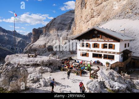 Rifugio Camillo Giussani Hutte, rifugio situato a forcella Fontananegra, gruppo montuoso di Tofane, con persone sedute all'aperto, con bel tempo in estate Foto Stock