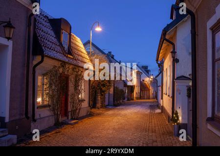 Vicolo acciottolato tra piccole case a fila al crepuscolo, Visby, isola di Gotland, Svezia Foto Stock