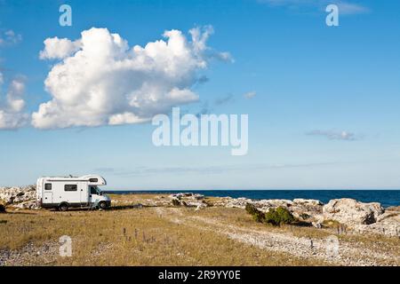 Vista laterale di una casa automobilistica accampata sulla spiaggia vicino al mare sotto le nuvole nel cielo. Isola di Gotland, Svezia. Foto Stock