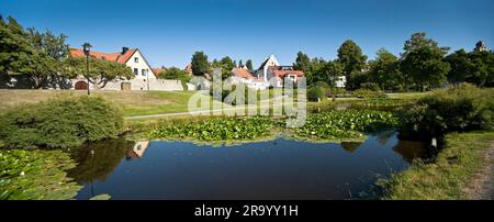 Vista di Almedalen con stagno e case circondate da alberi a distanza, Visby, Gotland, Svezia Foto Stock