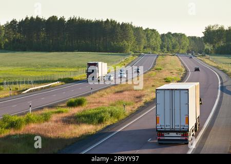 Rear shot of vehicles on country highway with trees in the background Foto Stock