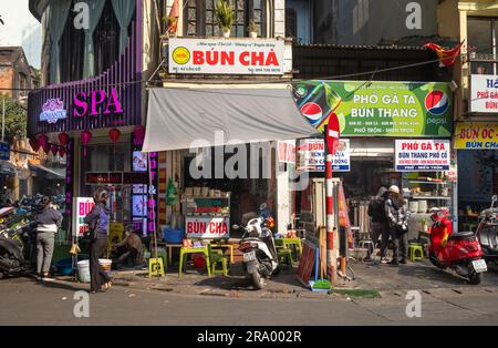La gente curiosa tra i piccoli ristoranti e negozi del centro storico di Hanoi, Vietnam. Foto Stock