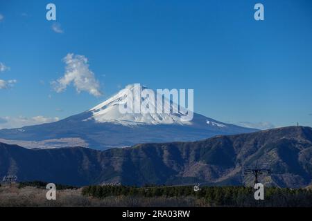 Monte Fuji a forma di cono innevato e funivia Owakudani visti da Hakone, Giappone, a dicembre Foto Stock