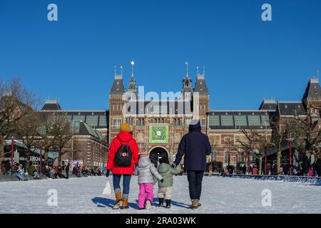 Famiglia e bambini che camminano sulla neve verso il Rijksmuseum, Amsterdam, Paesi Bassi Foto Stock