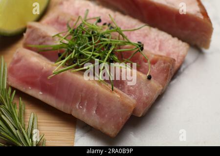 Pezzi di deliziosa bistecca di tonno con microgreen e rosmarino a bordo, primo piano Foto Stock