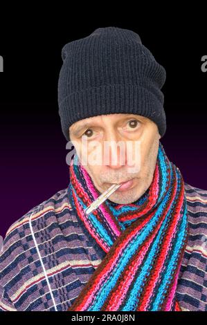 Uomo malato con l'influenza e la temperatura, che indossa un cappello e una sciarpa di lana, su sfondo scuro Foto Stock