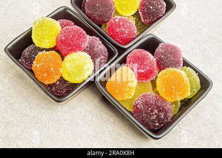 Gelatina di frutta colorata in piccole tazze di ceramica nera, su un tessuto canapa Foto Stock