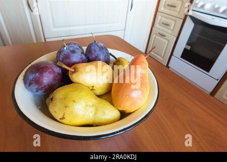 Tabella con una ciotola piena di pulire le pere e prugne in cucina Foto Stock