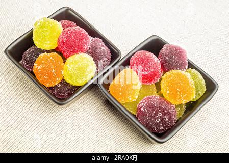 Gelatina di frutta colorata in piccole tazze di ceramica nera, su un tessuto canapa Foto Stock