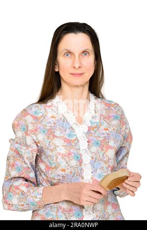 Donna adulta pettinare capelli lunghi marrone con un pettine di legno, isolato su sfondo bianco Foto Stock