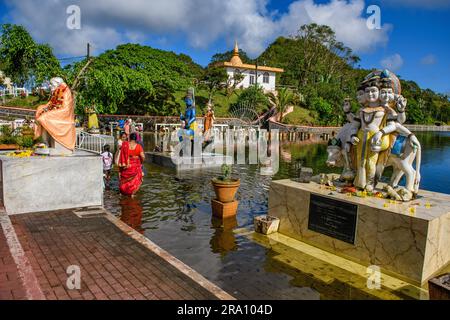 Figura della divinità indù destra figura di sbarramento scultura di Dattatreya incarnazione della trinità Brahma Vishnu Shiva, sullo sfondo i pellegrini di sinistra rendono omaggio Foto Stock