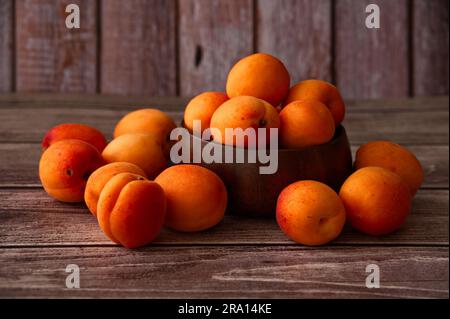 Albicocche mature in un recipiente di legno su sfondo di legno Foto Stock