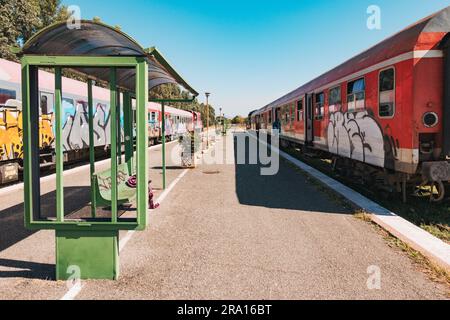 Locomotive diesel e vecchie carrozze coperte di graffiti aspettano di partire alla stazione ferroviaria di Durrës, sulla costa albanese Foto Stock