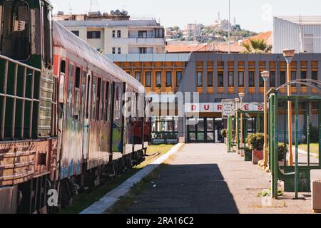 Locomotive diesel e vecchie carrozze coperte di graffiti aspettano di partire alla stazione ferroviaria di Durrës, sulla costa albanese Foto Stock