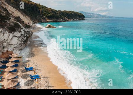 Lettini e ombrelloni pronti per i turisti sulle rive turchesi della spiaggia di Pulëbardha a Ksamil, Albania Foto Stock
