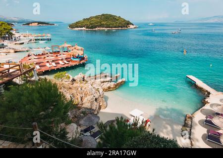 Lettini, ombrelloni e acque turchesi che aspettano i turisti a Rilinda Beach, Ksamil, Albania Foto Stock