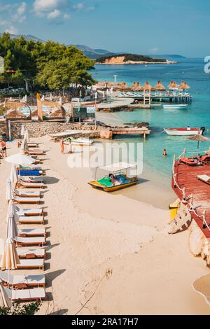 Lettini, ombrelloni e acque turchesi che aspettano i turisti a Rilinda Beach, Ksamil, Albania Foto Stock