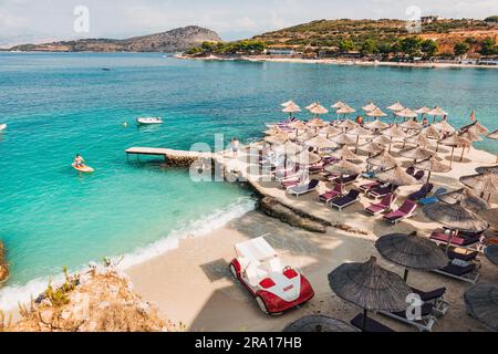 Lettini, ombrelloni e acque turchesi che aspettano i turisti a Rilinda Beach, Ksamil, Albania Foto Stock