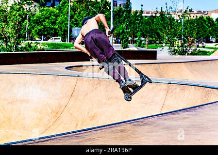 Giovane che pratica lo Scootering (Freestyle Scootering) nel nuovo Skatepark del parco centrale di Igualada, Barcellona, Spagna Foto Stock