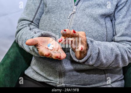 Donna anziana con diverse pillole in mano per prendere il farmaco Foto Stock