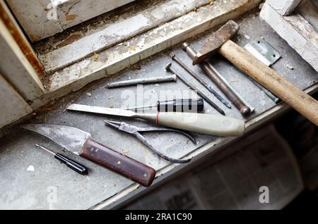 Riparazione del vecchio finestrino danneggiato o smontaggio prima di installare il nuovo primo piano. Riparazione di un telaio di una finestra, utilizzando strumenti per la ristrutturazione di vecchie finestre Foto Stock