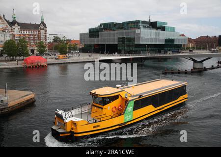 Kopenhagen, Danimarca. 28 giugno 2023. Il traghetto del porto di Copenaghen passa tra il Lille Langebro (piccolo ponte lungo) e il Langebro (ponte lungo). Sullo sfondo si può vedere l'edificio Blox, che ospita anche il Danish Architecture Center. A sinistra si può vedere il tetto rosso di "The Raft", una costruzione in occasione del prossimo congresso di architetti. Copenaghen ospiterà il 28° Congresso Mondiale degli Architetti nei prossimi giorni. (Al dpa "edificio sano" - quanto può essere sostenibile l'architettura?") Crediti: Steffen Trumpf/dpa/Alamy Live News Foto Stock