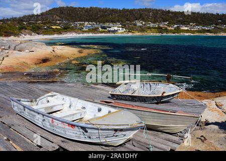 barche a remi di legno lungo il molo in una giornata di sole nel pittoresco porto di bicheno, tasmania, australia Foto Stock