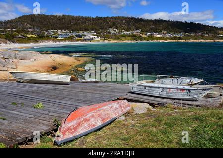 barche a remi di legno lungo il molo in una giornata di sole nel pittoresco porto di bicheno, tasmania, australia Foto Stock