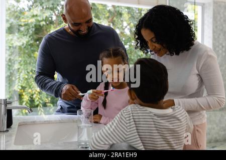 I genitori, i figli e la figlia che si lavano i denti in bagno la mattina Foto Stock