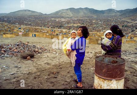 Perù, Lima; donne e bambini in una grande baraccopoli con case fatte di canna. Foto Stock