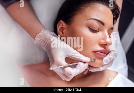 Pulizia professionale estetista dell'acne della donna durante la procedura anti invecchiamento in clinica di bellezza Foto Stock