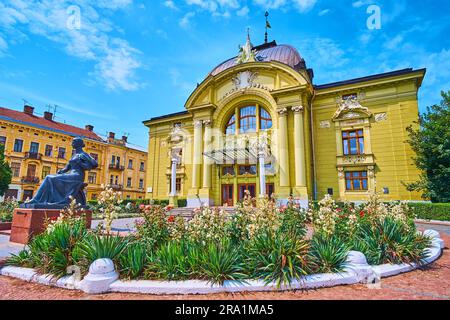 Le splendide aiuole con yucca in fiore e rose di fronte alla statua di Olga Kobylianska e al teatro musicale e drammatico, Chernivtsi, Ucraina Foto Stock