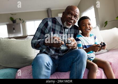 Nonno e nipote afro-americani seduti sul divano a giocare ai videogiochi Foto Stock
