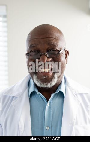 Ritratto di un medico afro-americano anziano felice che indossa un camice da laboratorio e occhiali Foto Stock