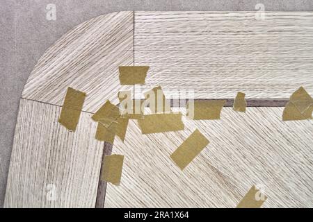 Impiallacciatura articolata con nastro in tela per il piano del tavolo da pranzo con motivo geometrico sul banco di lavoro nella vista ravvicinata superiore dell'officina Foto Stock