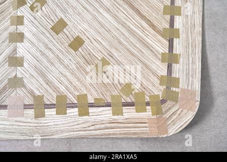 Impiallacciatura articolata con nastro in tela per il piano del tavolo da pranzo con motivo geometrico sul banco di lavoro nella vista ravvicinata superiore dell'officina Foto Stock