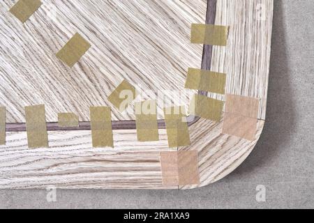 Impiallacciatura articolata con nastro in tela per il piano del tavolo da pranzo con motivo geometrico sul banco di lavoro nella vista ravvicinata superiore dell'officina Foto Stock